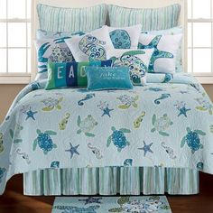 a bed covered in blue and green comforters with sea animals on the coverlet