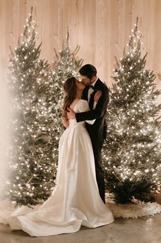 a bride and groom kissing in front of a christmas tree