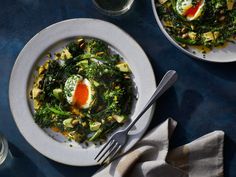 two plates with eggs and vegetables on them next to silverware, glasses and utensils