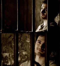 a man standing behind bars in a jail cell