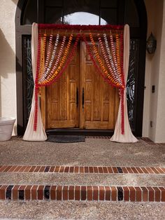 an entrance decorated with orange and white garlands for a wedding or special occasion in front of a door