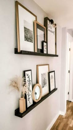 some framed pictures are hanging on the wall next to a wooden floor and white walls