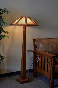 a wooden floor lamp sitting next to a couch in a living room with a potted plant