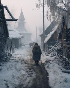 a woman walking down a snow covered street in front of some wooden shacks and buildings