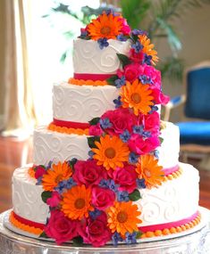 a multi - tiered wedding cake with colorful flowers on the top and bottom layer