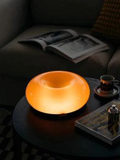 a table with a lamp on top of it next to a book and coffee cup