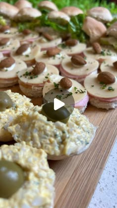 an assortment of appetizers are displayed on a wooden board with green olives