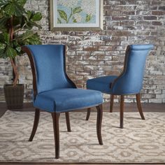 two blue chairs sitting next to each other in front of a brick wall with a potted plant