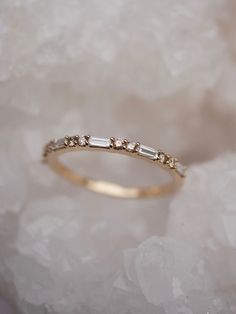 a gold ring with three stones on it sitting on top of some white rocks and ice crystals