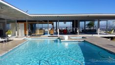 an outdoor swimming pool in front of a large windowed building with glass doors on the side