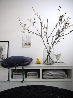 a vase filled with flowers sitting on top of a table next to pillows and blankets