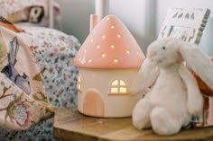 two stuffed animals sitting on a table next to a doll house with a pink roof