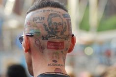 the back of a man's head with many tattoos on his face and neck