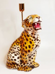 a ceramic leopard figurine with a toothbrush in it's mouth, on a white background