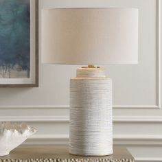 a white lamp sitting on top of a table next to a vase and seashell