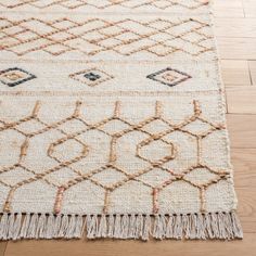 an area rug with fringes on the floor and wooden floors in front of it