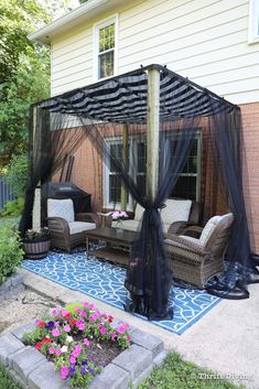 a patio covered in black netting and furniture