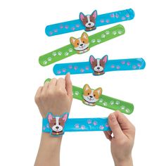 a person is holding up four dog bracelets with different designs on them and their hands are in the air