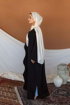 A timeless silhouette with dimensional texture and a curving detail, this black abaya will have you feeling effortlessly elegant for every Ramadan occasion. Complete the look with our black underdress or rock it alone. Pairs perfectly with our new Celestial Phases hijab and Qamar Black. Available in a range of sizes and lengths that include sizes 2 to 16. Lulu is a size US4 and 5'3, wearing S/M Short Maleeha is a size US14 and 5'4, wearing XL Short. Pocket Abaya, Gold Abaya, Black Hijab Outfit, Trip Fits, Abaya Black, Best Jersey, Petal Dust, Hijabi Fits, Black Abaya