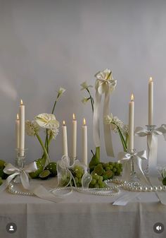 a table topped with lots of white flowers next to candles and pearls on top of it