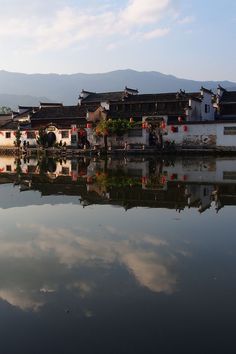 a body of water with buildings and mountains in the background