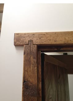 an open wooden door on the side of a white wall with a mirror above it