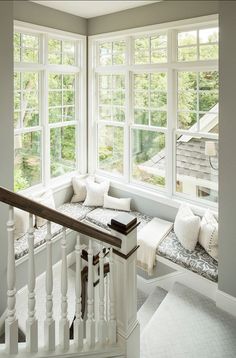 a window seat with pillows on it next to a stair case