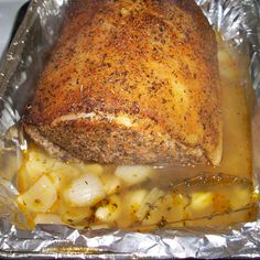 a roasting pan filled with meat and potatoes on top of foil covered in seasoning