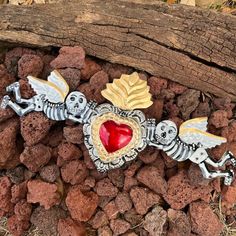 a heart shaped brooch sitting on top of rocks