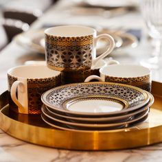 a table topped with plates and cups on top of a gold tray