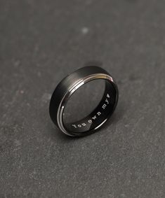 a black and silver ring with the words you're loved on it, sitting on a gray surface