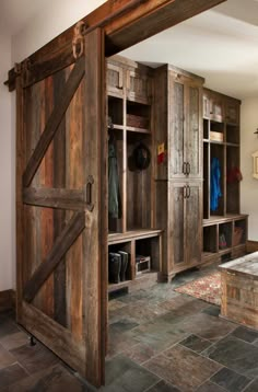 an open barn door leading to a bedroom with stone flooring and built - in shelving