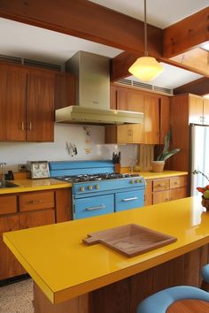 a kitchen with yellow counter tops and blue chairs