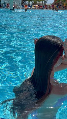 a woman in a swimming pool with her hands up to her face and the back of her head