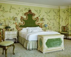 the bedroom is decorated in green and white colors with an ornate headboard, foot stools, and bed