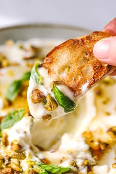 a piece of toasted bread being dipped with cream cheese and spinach leaves in a skillet