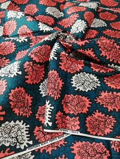 a blue and red floral print fabric with white flowers on the center, as well as black background