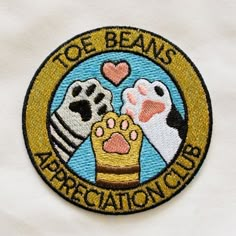 an embroidered patch with the words toe beans appreciation club and two dogs holding a heart