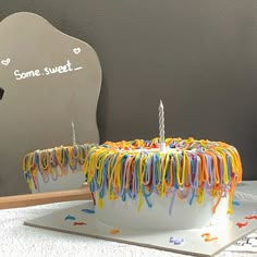 a birthday cake that has been decorated with streamers and a single candle on it