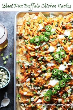 a tray filled with chicken nachos next to two cups of beer and other food