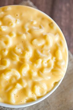 a white bowl filled with macaroni and cheese on top of a wooden table