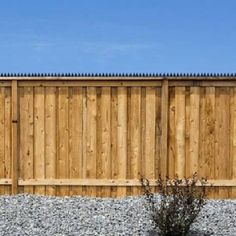 a wooden fence next to a gravel field