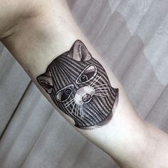 a black and white cat tattoo on the arm