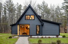 a blue house in the woods with lots of grass and trees around it's front door