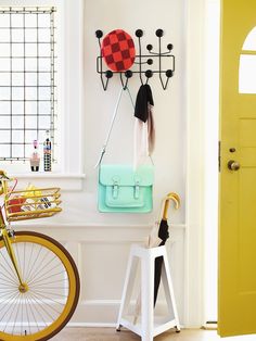 a bicycle is parked in front of a wall mounted coat rack with hats and umbrellas on it