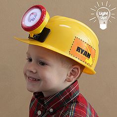 a young boy wearing a yellow hard hat with a light on it's head