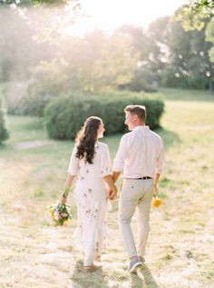 a man and woman holding hands walking in the grass