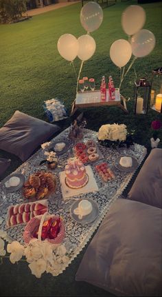 a table with balloons and food on it in the middle of a field at night