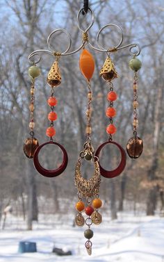 a wind chime hanging from the side of a window in front of snow covered trees