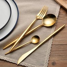 gold colored utensils are sitting on a place mat next to a plate and silverware